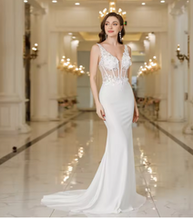 Woman in a white evening gown standing in an elegant indoor setting.