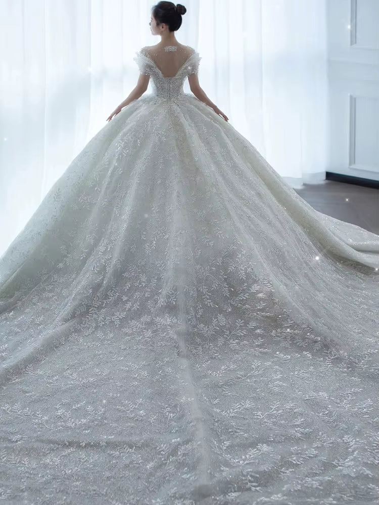 Elegant white wedding dress with a long train in a softly lit room.